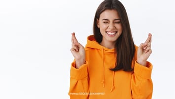 Persona feliz con dedos cruzados simbolizando suerte 