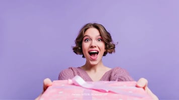 Mujer con expresion de sorprendida con regalo en las manos 
