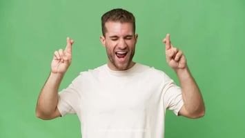 Hombre feliz y con dedos cruzados manifestando suerte 