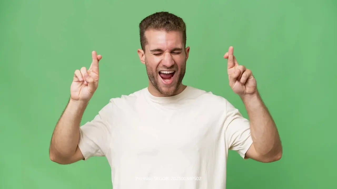 Hombre feliz con dedos cruzados manifestando suerte