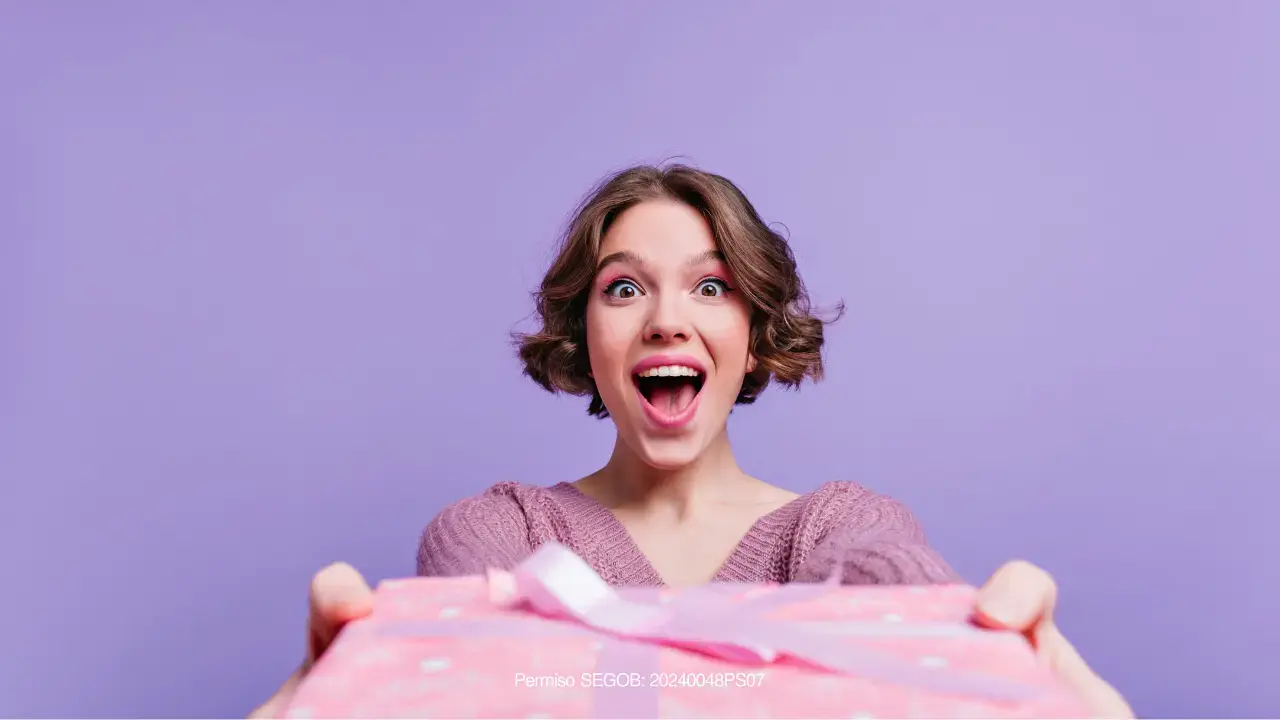 Mujer con expresion de sorprendida con regalo en las manos 