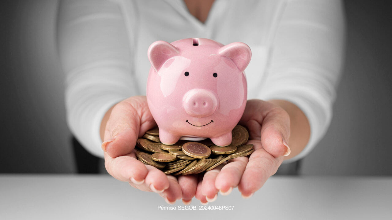 persona sosteniendo una alcancia y dinero 